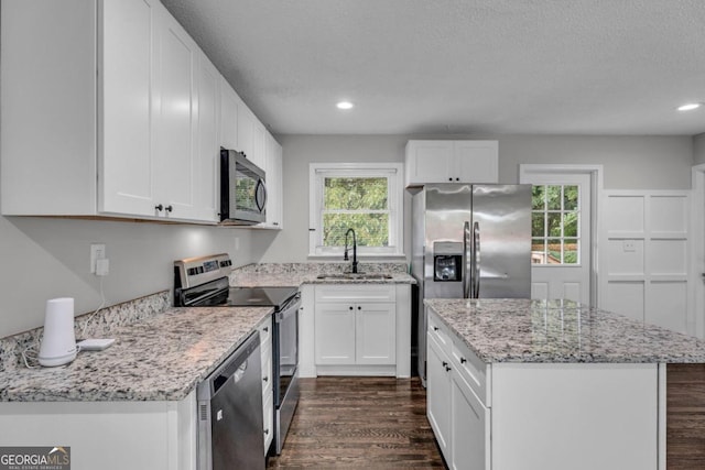 kitchen with appliances with stainless steel finishes, sink, white cabinets, and dark hardwood / wood-style flooring