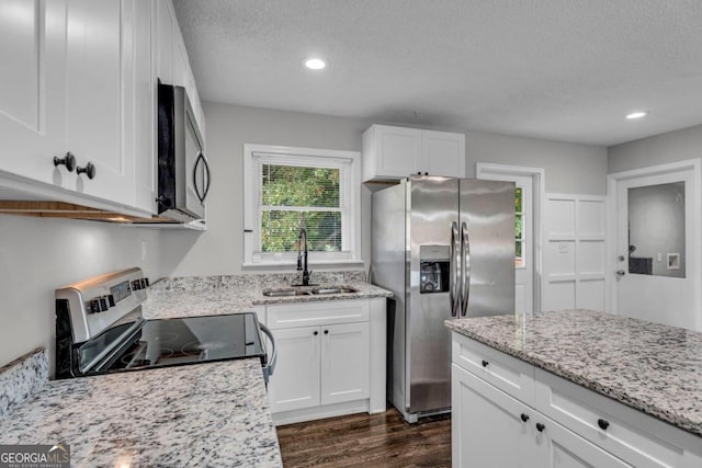 kitchen with dark wood-type flooring, sink, light stone counters, appliances with stainless steel finishes, and white cabinets