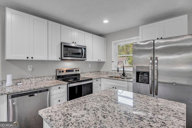 kitchen featuring light stone counters, appliances with stainless steel finishes, sink, and white cabinets