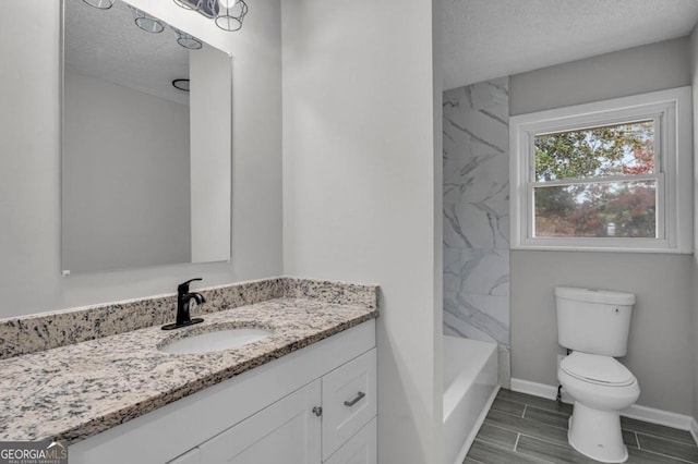 full bathroom featuring vanity, tiled shower / bath, toilet, and a textured ceiling