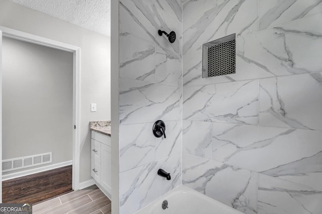 bathroom featuring tiled shower / bath combo, vanity, and a textured ceiling