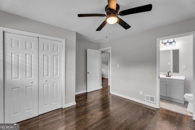 unfurnished bedroom with ensuite bathroom, dark hardwood / wood-style floors, sink, a textured ceiling, and a closet