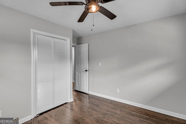 unfurnished bedroom featuring ceiling fan, dark wood-type flooring, a closet, and a textured ceiling