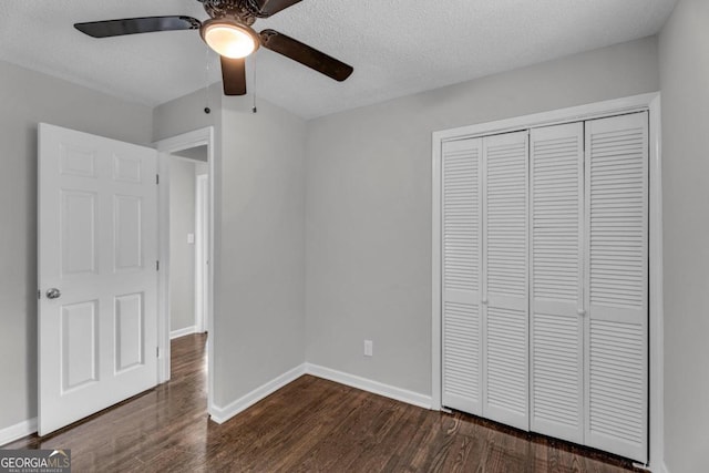 unfurnished bedroom with dark wood-type flooring, ceiling fan, a closet, and a textured ceiling