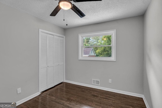 unfurnished bedroom with ceiling fan, dark wood-type flooring, a closet, and a textured ceiling