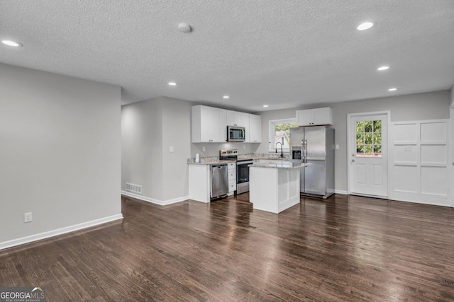 kitchen with sink, stainless steel appliances, dark hardwood / wood-style floors, a center island, and white cabinets