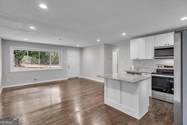 kitchen with a kitchen island, appliances with stainless steel finishes, dark hardwood / wood-style floors, white cabinetry, and light stone countertops