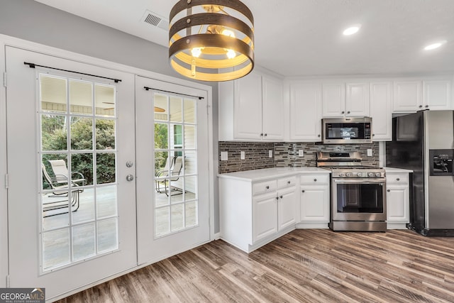 kitchen featuring decorative backsplash, light hardwood / wood-style flooring, white cabinets, and stainless steel appliances