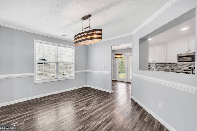 unfurnished dining area with a chandelier, a textured ceiling, dark hardwood / wood-style flooring, and crown molding