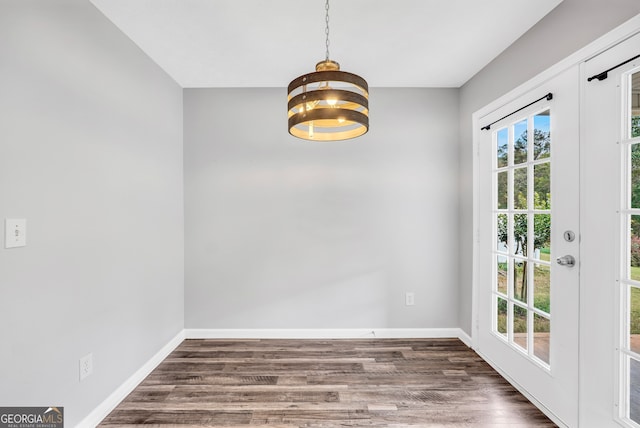 unfurnished dining area with a notable chandelier, dark hardwood / wood-style flooring, and french doors