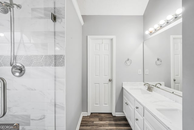 bathroom featuring tiled shower, wood-type flooring, and vanity