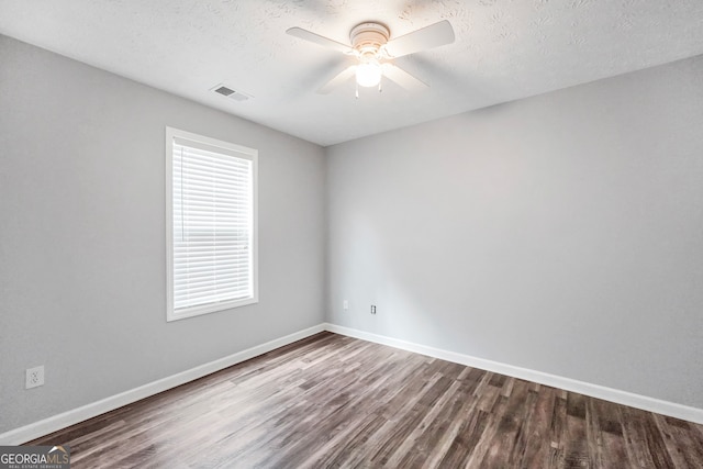 empty room featuring dark hardwood / wood-style floors, ceiling fan, and a textured ceiling