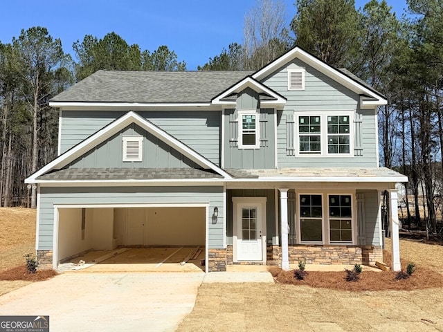 view of front of home featuring board and batten siding, a shingled roof, a garage, stone siding, and driveway