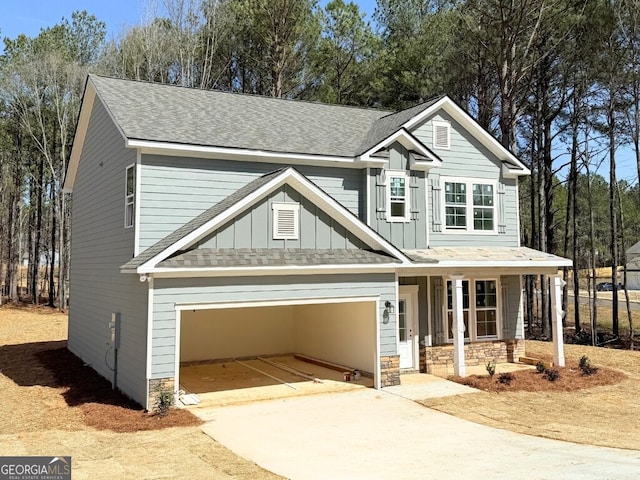 view of front of house with stone siding, covered porch, board and batten siding, and concrete driveway