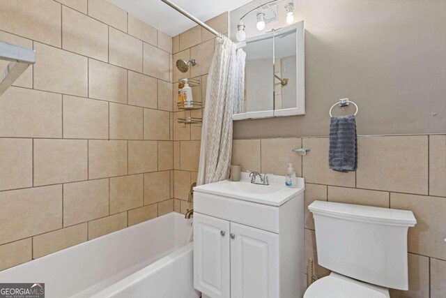 full bathroom with vanity, shower / tub combo, tile walls, and toilet