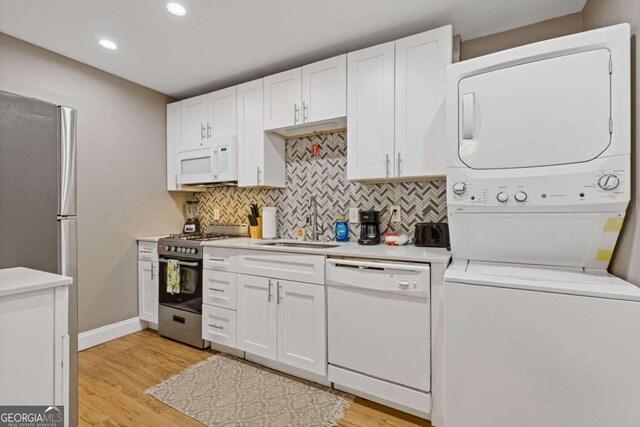 kitchen with stacked washer / dryer, white cabinetry, sink, and appliances with stainless steel finishes