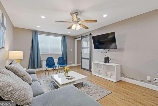 living room with hardwood / wood-style floors, ceiling fan, and a barn door