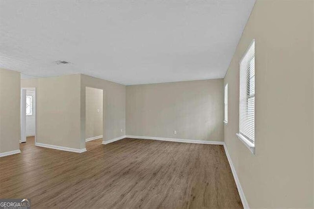 unfurnished room with a wealth of natural light and dark wood-type flooring