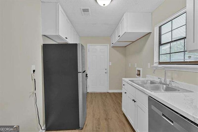 kitchen with white cabinets, sink, light hardwood / wood-style flooring, a textured ceiling, and appliances with stainless steel finishes