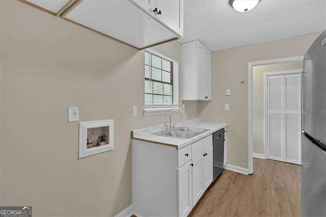 kitchen with appliances with stainless steel finishes, a textured ceiling, sink, light hardwood / wood-style floors, and white cabinetry