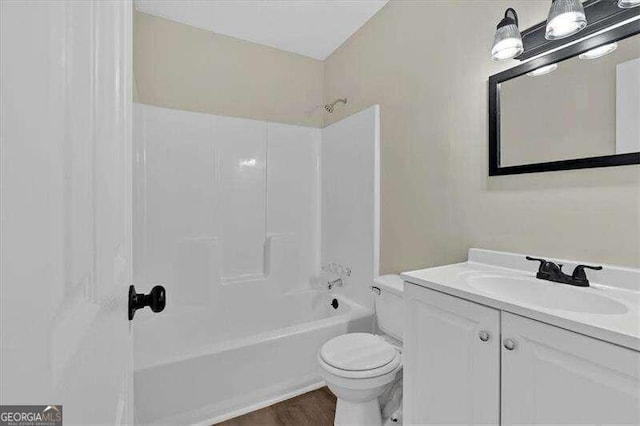 full bathroom with shower / washtub combination, vanity, hardwood / wood-style floors, and toilet