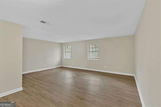 empty room with dark hardwood / wood-style flooring and a textured ceiling