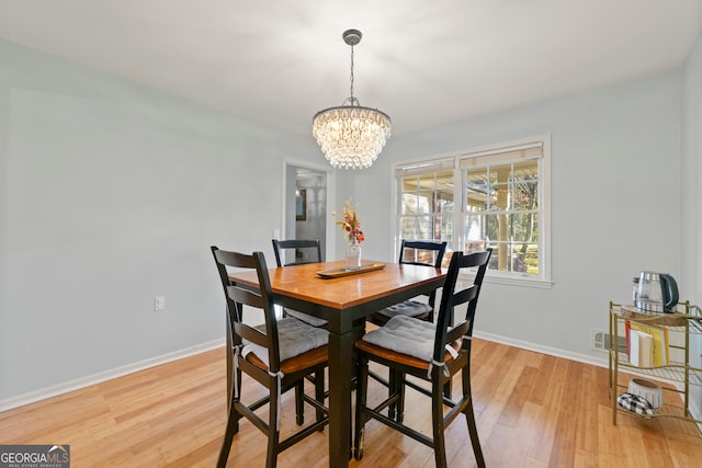 dining room with light wood-type flooring and a chandelier