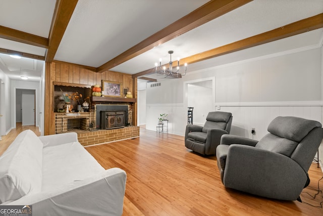 living room featuring beam ceiling, a fireplace, hardwood / wood-style floors, and ornamental molding