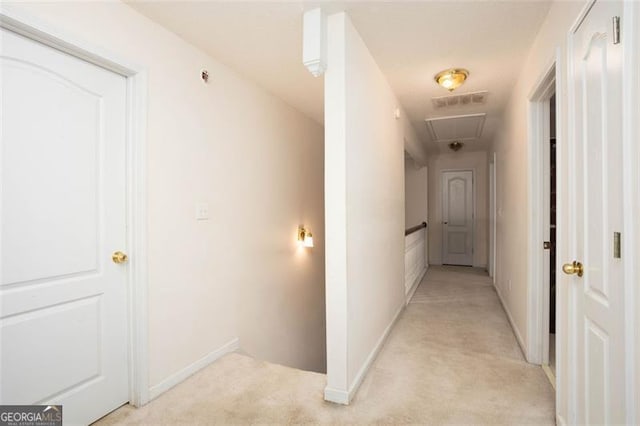 corridor with light carpet, visible vents, attic access, and baseboards