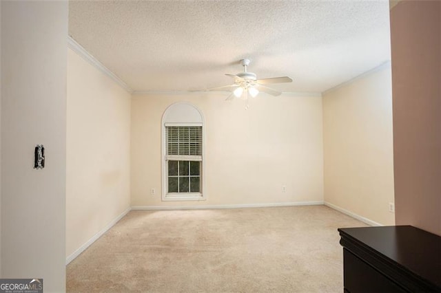 unfurnished room featuring a textured ceiling, ornamental molding, a ceiling fan, and light colored carpet