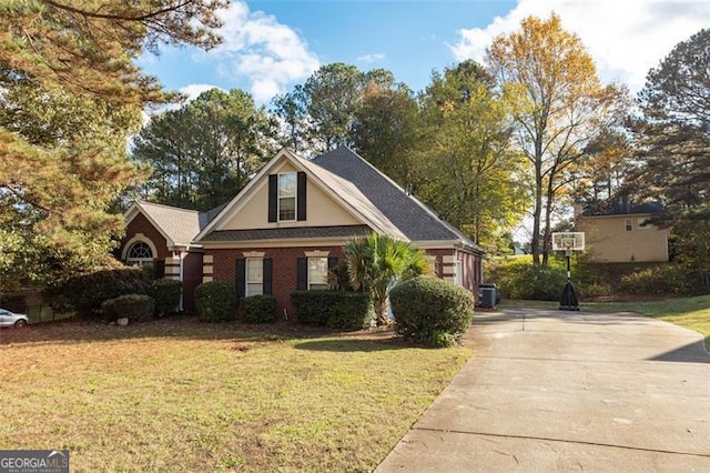 view of front facade featuring central AC unit, driveway, brick siding, and a front yard