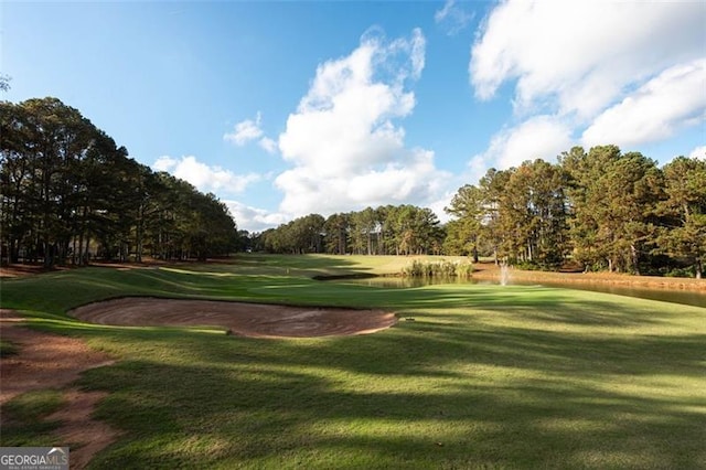 view of property's community with golf course view and a lawn