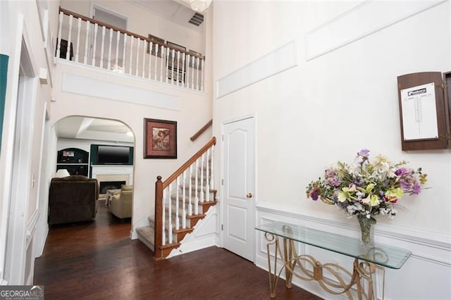 stairs featuring visible vents, a fireplace, wood finished floors, and a towering ceiling