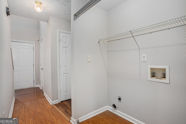 washroom with hookup for an electric dryer, hardwood / wood-style floors, a textured ceiling, and hookup for a washing machine