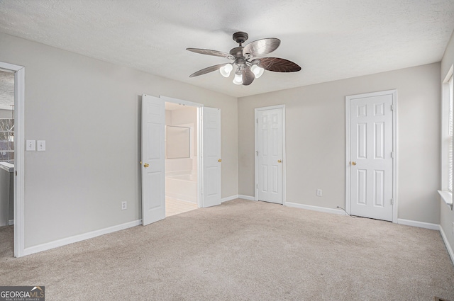 unfurnished bedroom with ensuite bath, ceiling fan, light colored carpet, and a textured ceiling