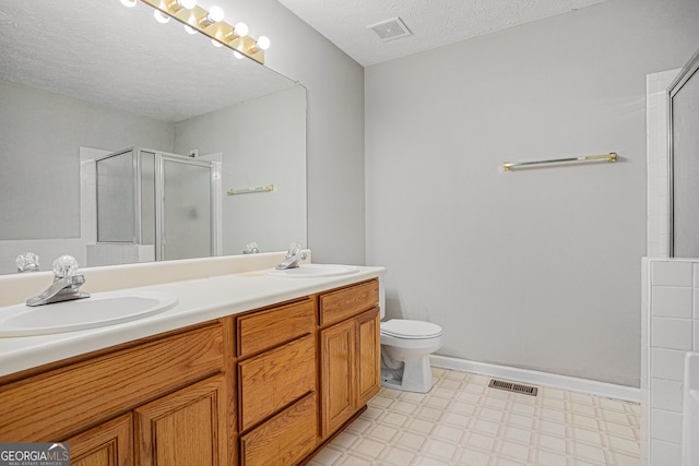 bathroom with vanity, a textured ceiling, toilet, and a shower with shower door