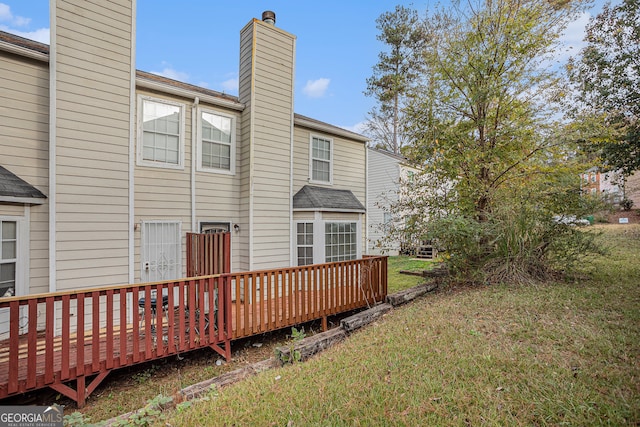 back of property featuring a yard and a wooden deck