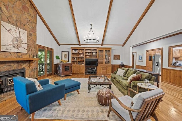 living room featuring light hardwood / wood-style flooring, beamed ceiling, high vaulted ceiling, a chandelier, and wooden walls