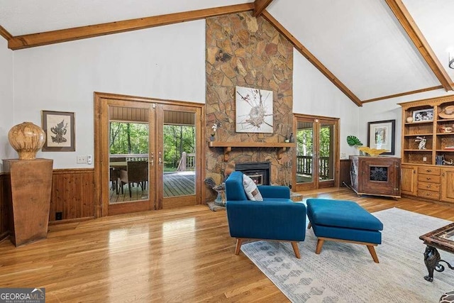 living room with a stone fireplace, a wealth of natural light, high vaulted ceiling, and light hardwood / wood-style floors