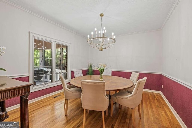 dining space featuring a chandelier, wood-type flooring, and crown molding