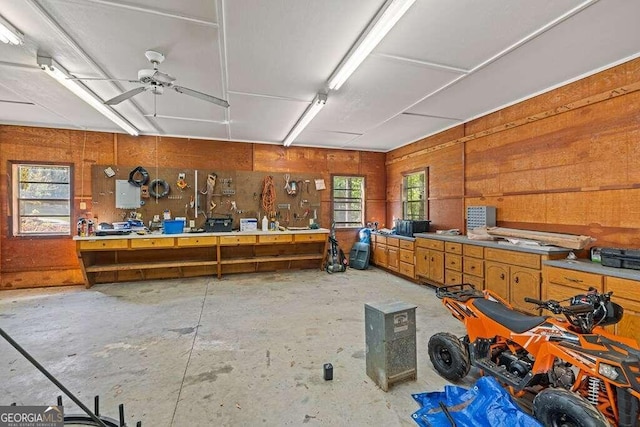 miscellaneous room featuring a workshop area, electric panel, ceiling fan, and concrete floors