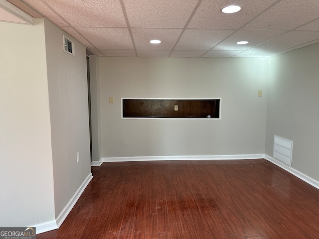 spare room with a paneled ceiling and dark wood-type flooring