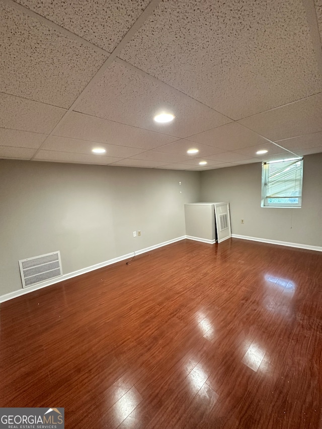 basement with a paneled ceiling and hardwood / wood-style flooring