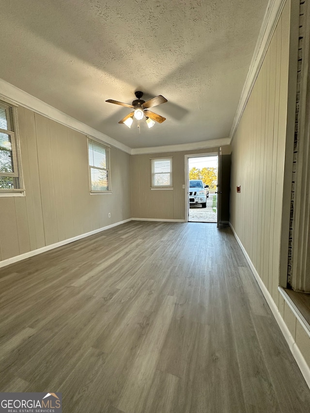 empty room with a textured ceiling, dark hardwood / wood-style floors, ceiling fan, and crown molding