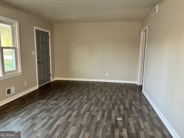 unfurnished room featuring a textured ceiling and dark hardwood / wood-style floors