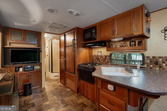 kitchen with decorative backsplash, stove, ventilation hood, black microwave, and sink