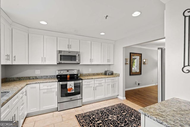 kitchen with light tile patterned flooring, white cabinets, and stainless steel appliances