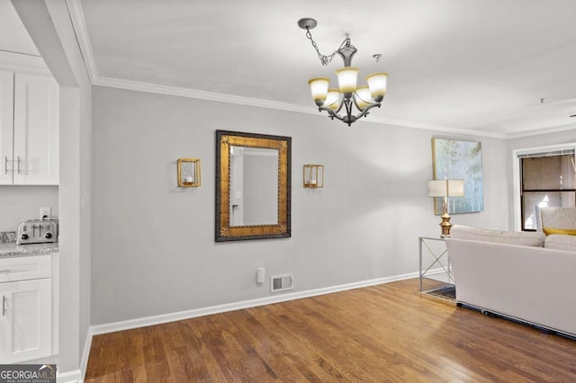 unfurnished living room with hardwood / wood-style flooring, crown molding, and a notable chandelier