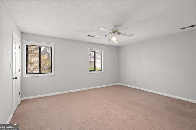 unfurnished room with ceiling fan, light colored carpet, and a textured ceiling