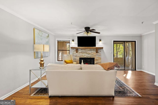 living room featuring hardwood / wood-style floors, a stone fireplace, ceiling fan, and ornamental molding